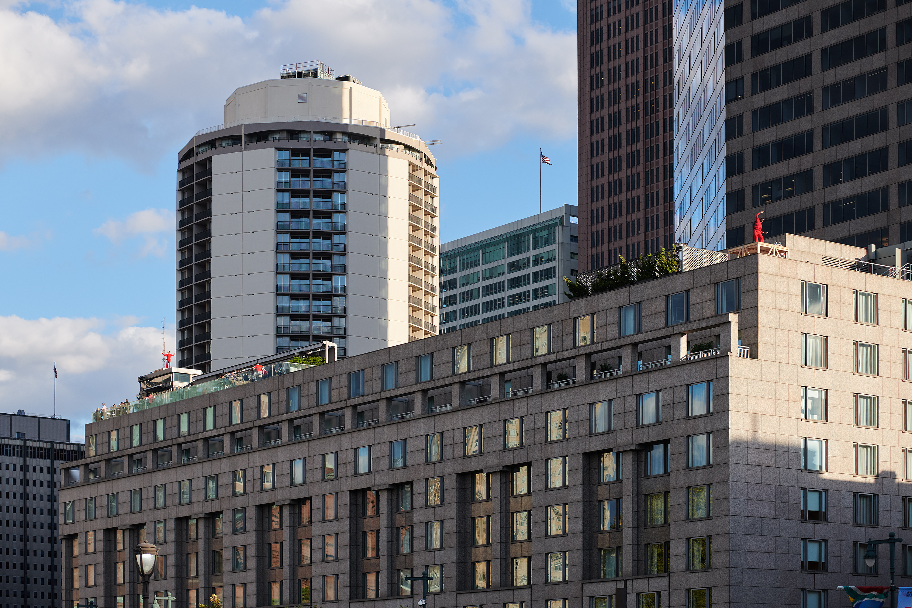 Landscape photo of Trisha Brown dancers in red on a roof. Photo: Albert Yee